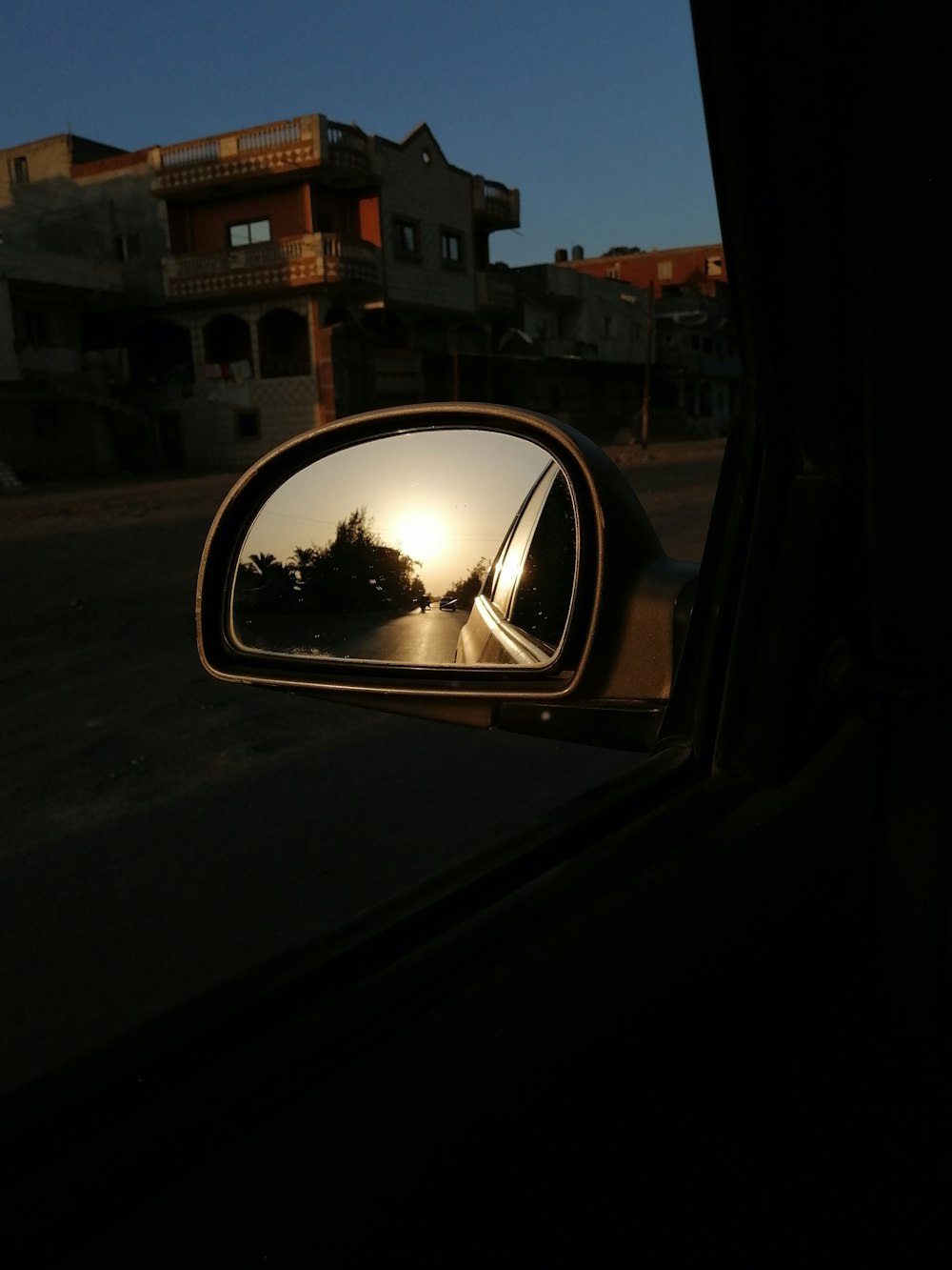 black car side mirror reflecting white concrete building during daytime