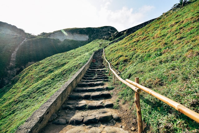 gray concrete stairs on green grass field near mountain during daytime