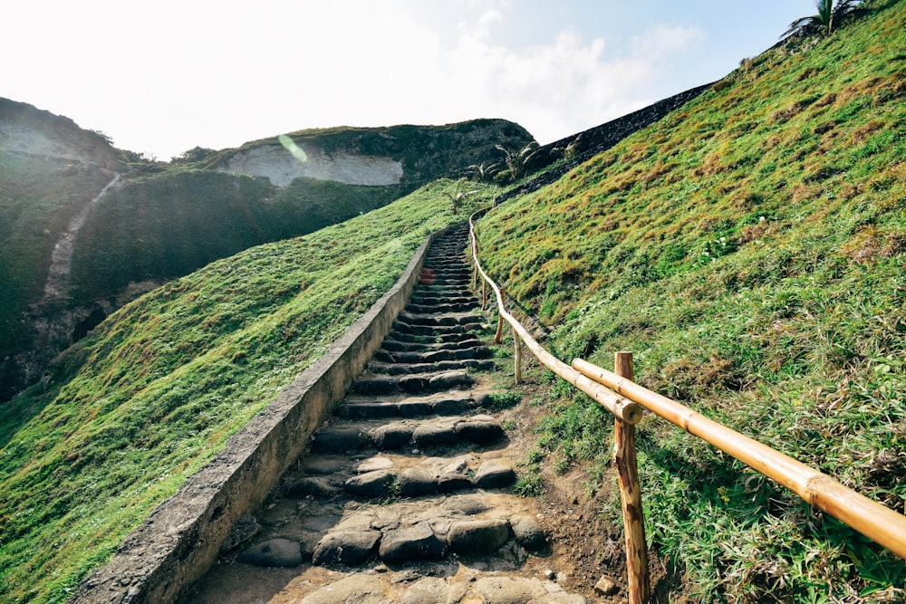 gray concrete stairs on green grass field near mountain during daytime