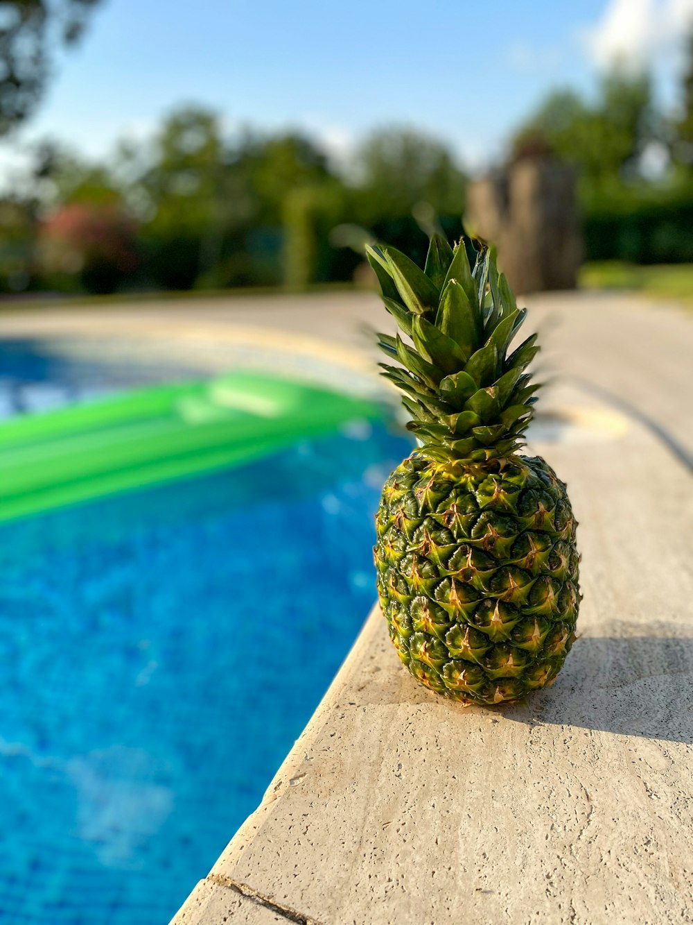 a pineapple sitting on the edge of a swimming pool