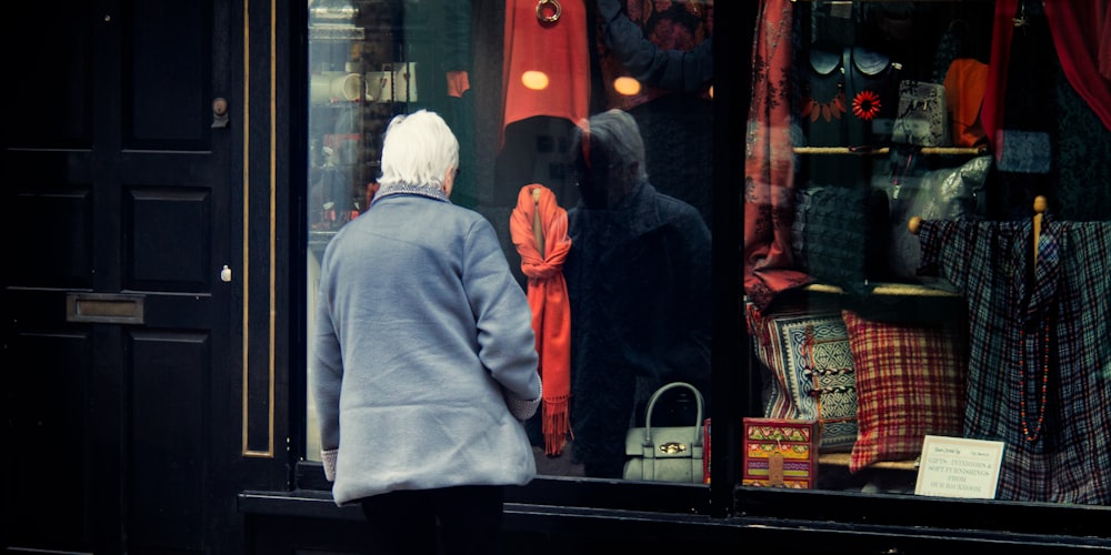 uomo in felpa con cappuccio grigia in piedi accanto al negozio