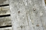 Weathered wooden planks with visible grain and rusted nails, creating a rustic and aged appearance.