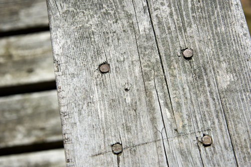 Weathered wooden planks with visible grain and rusted nails, creating a rustic and aged appearance.