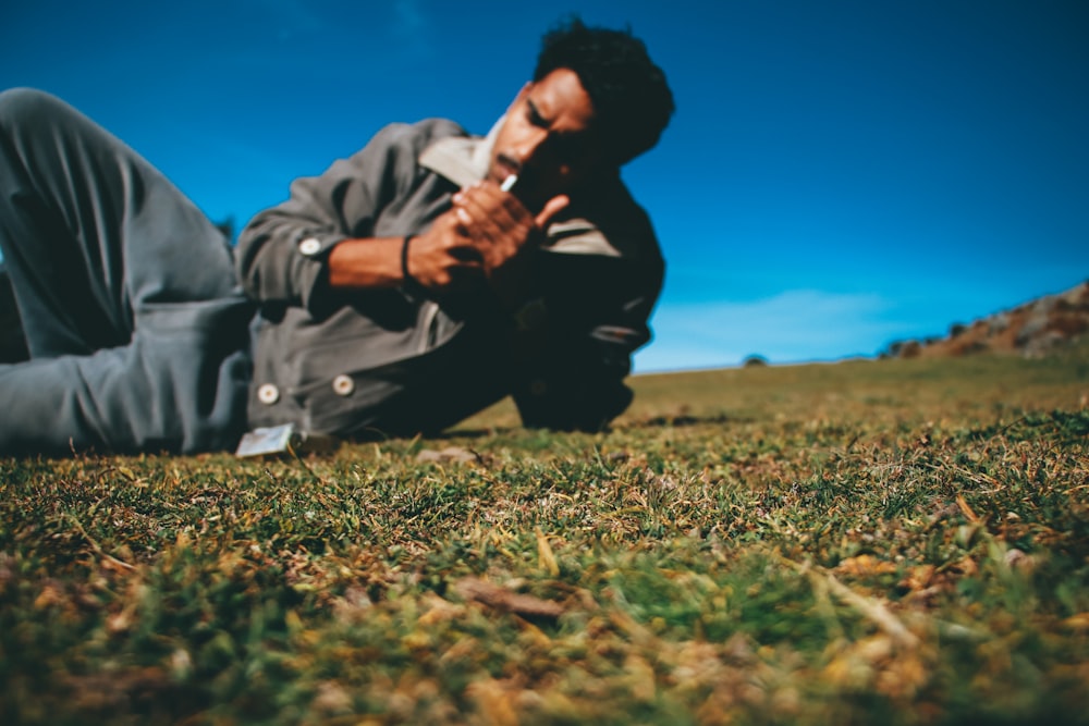 man in gray jacket sitting on green grass field during daytime