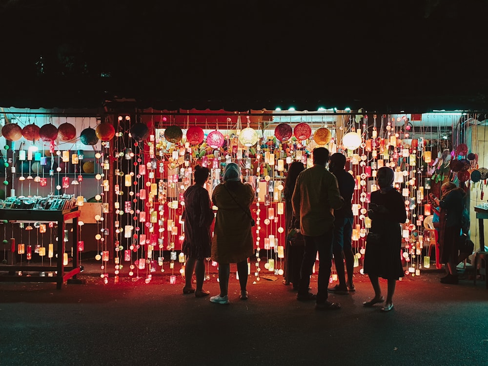 people in black suits standing on red and white string lights