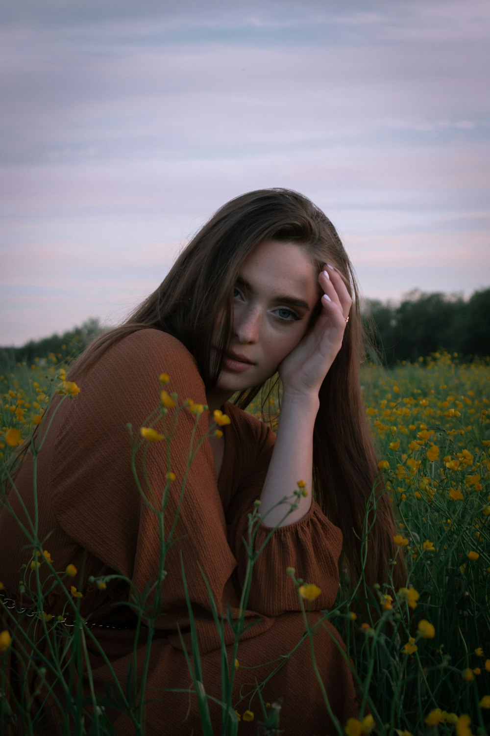 woman in orange long sleeve shirt covering her face with her hand