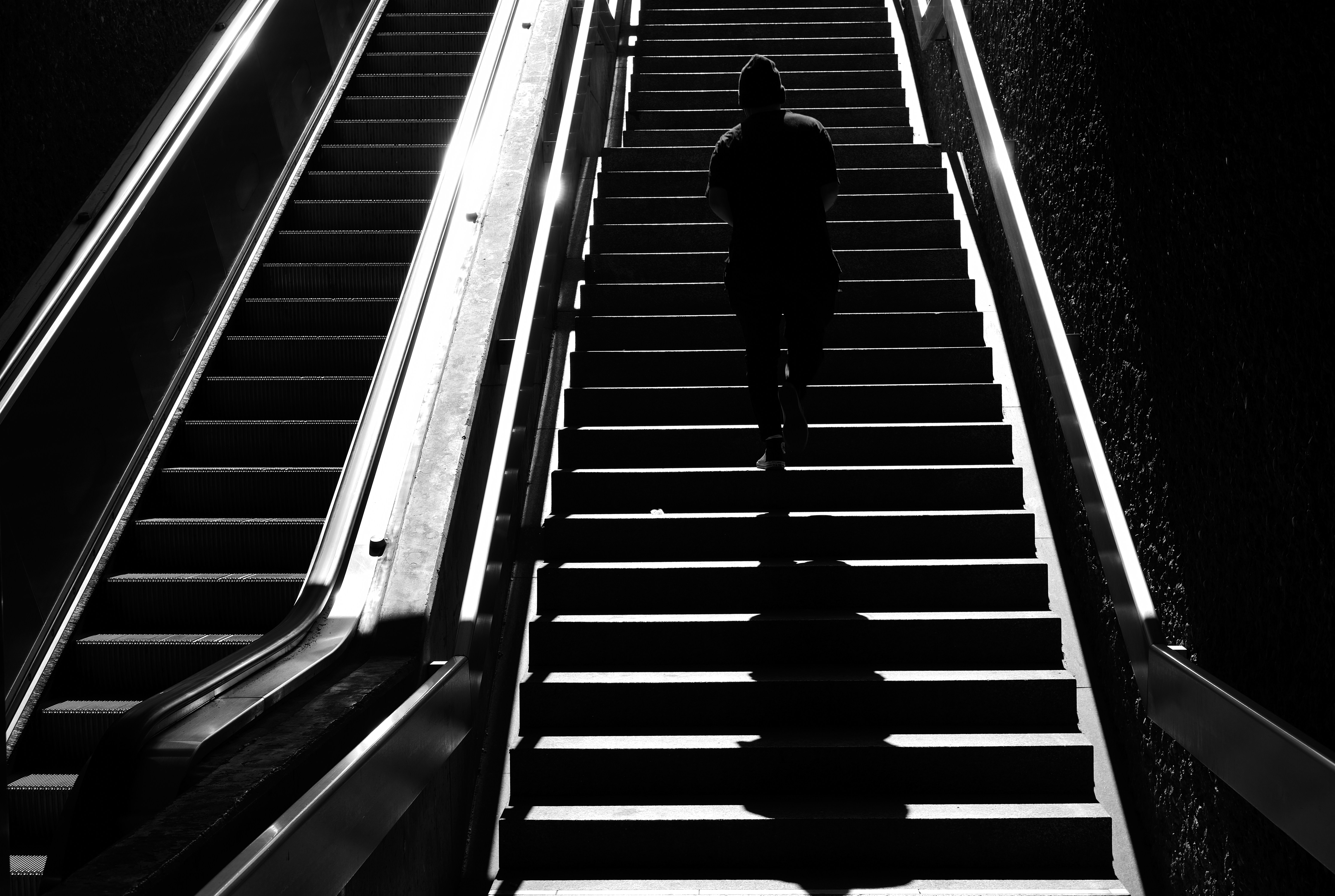 man in black jacket walking on escalator