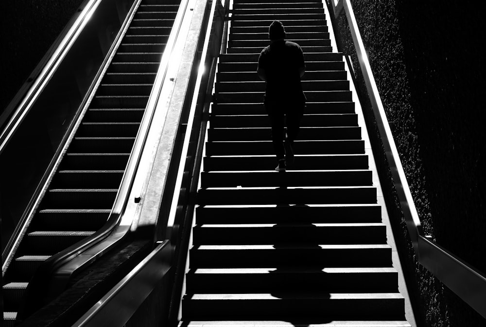 homem na jaqueta preta andando na escada rolante