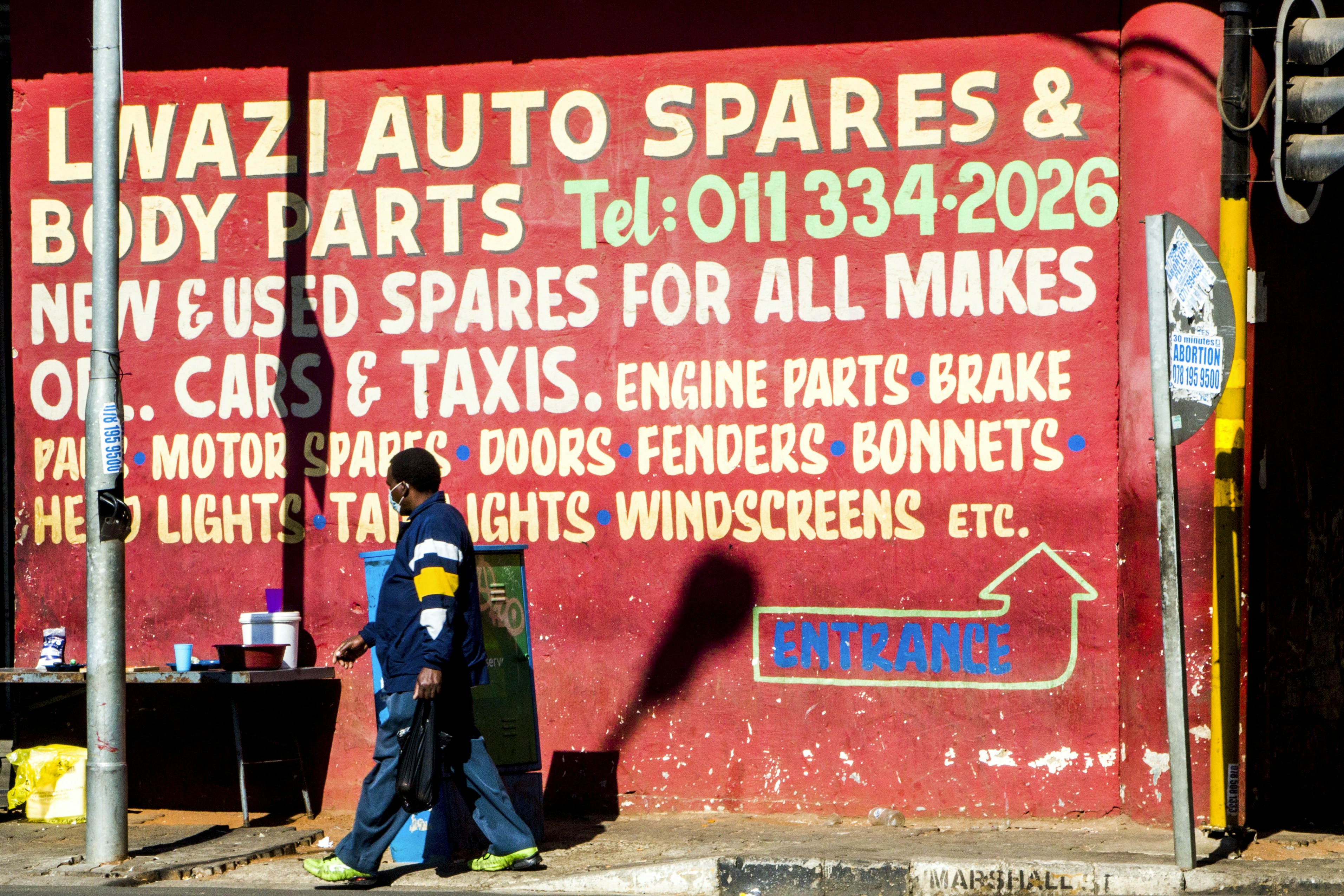 man in green and black jacket standing beside red and white wall