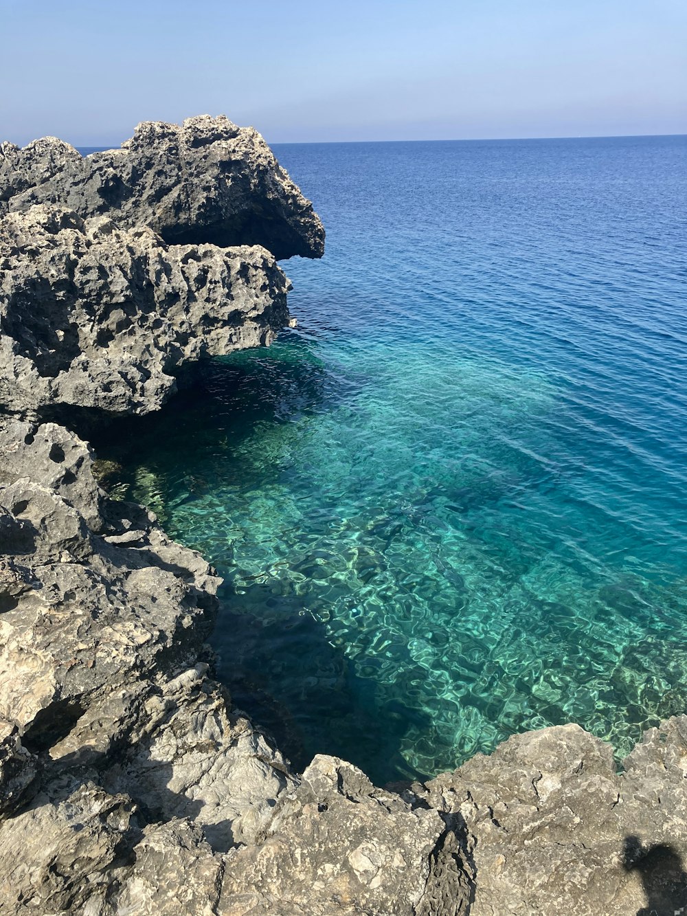 昼間の青い海に浮かぶ灰色の岩山