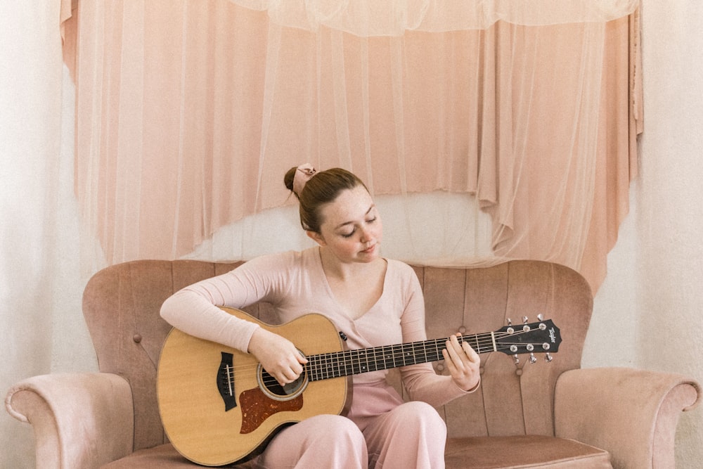 woman in white long sleeve shirt playing acoustic guitar
