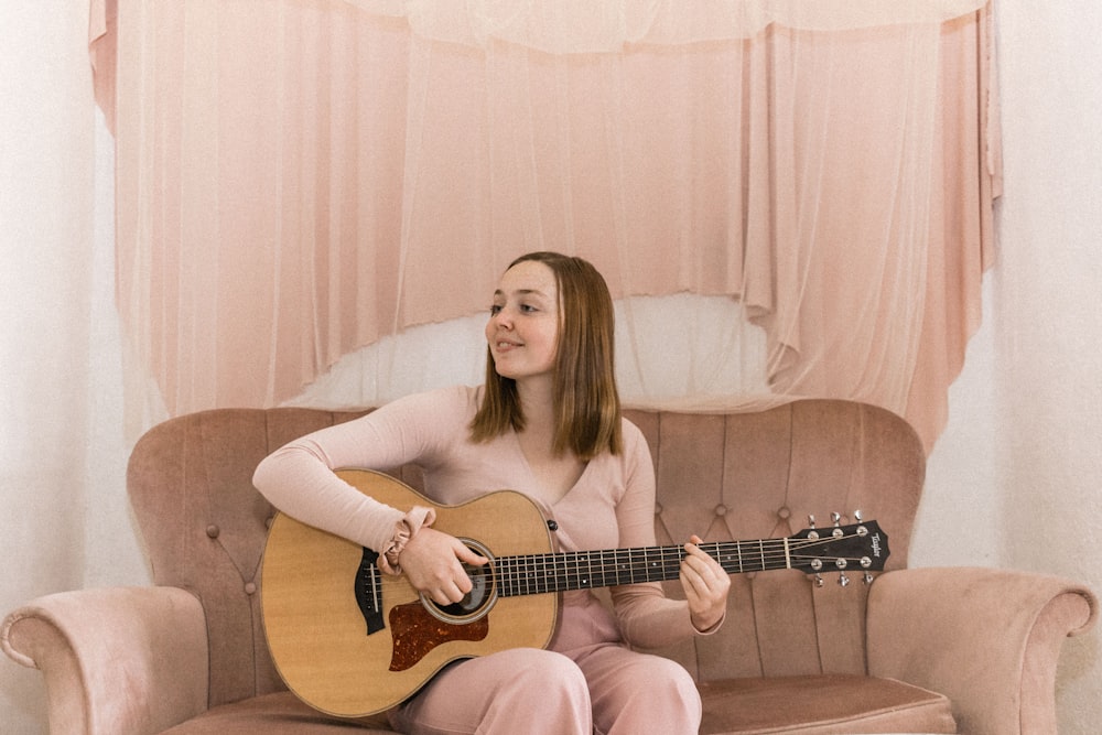 woman in white long sleeve shirt playing brown acoustic guitar