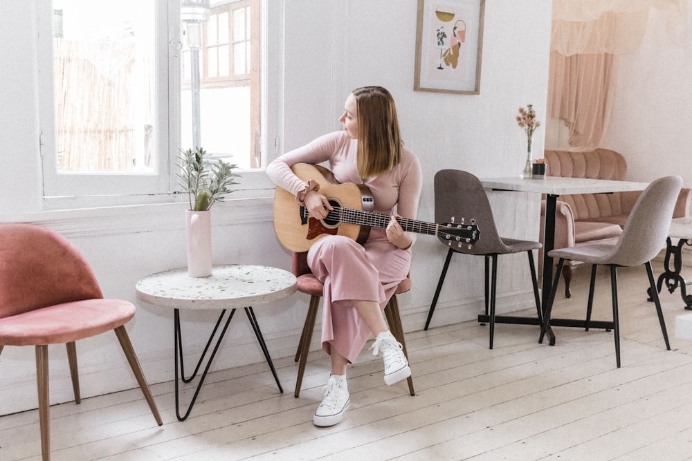 chica en vestido rosa tocando la guitarra