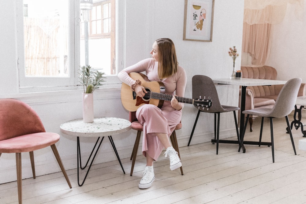 fille en robe rose jouant de la guitare