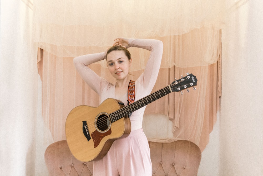 woman in pink sleeveless dress holding brown acoustic guitar