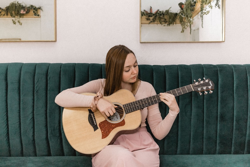 갈색 어쿠스틱 기타를 연주하는 분홍색 긴팔 셔츠를 입은 여자