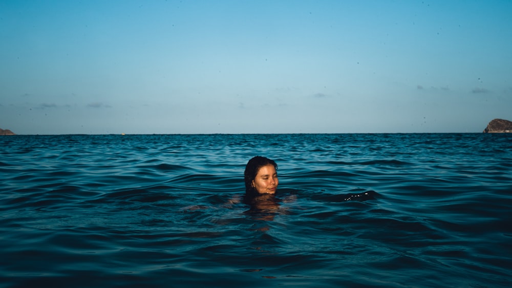 woman in water under blue sky during daytime