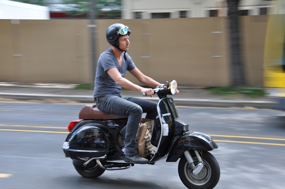 Uomo in polo blu che guida la moto nera durante il giorno