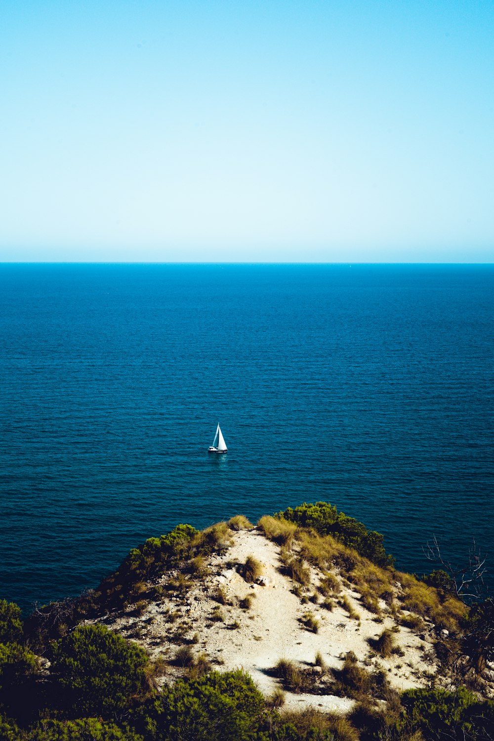 white sailboat on blue sea under white sky during daytime