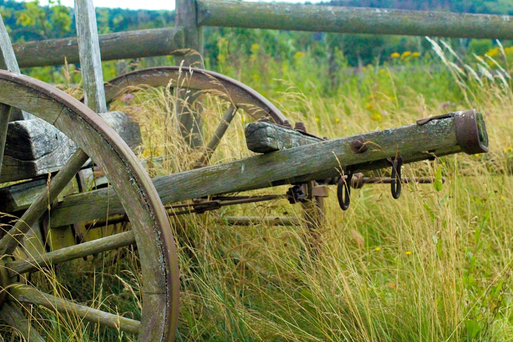 brown wooden carriage wheel on green grass field during daytime
