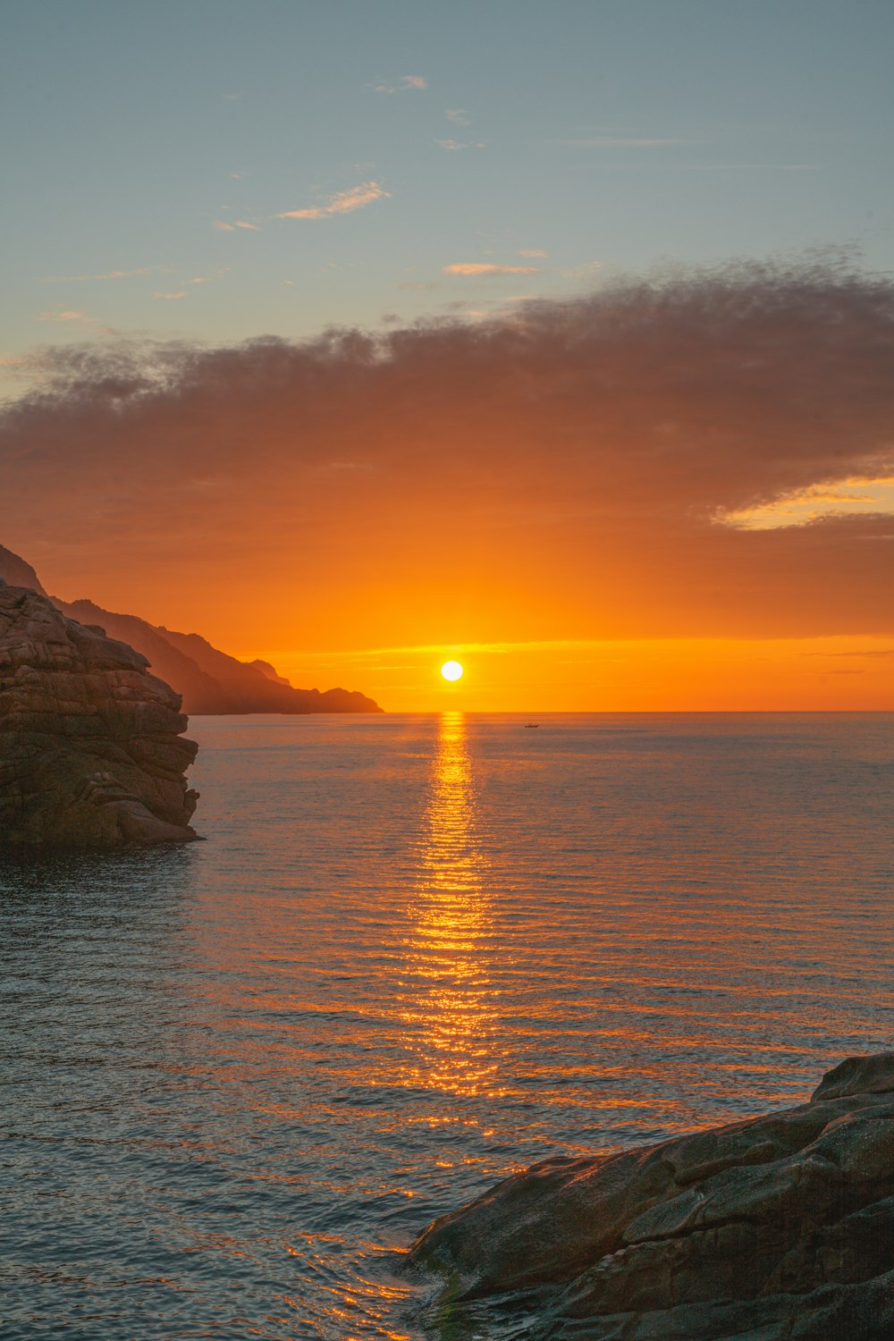 Formación de roca marrón en el mar durante la puesta del sol