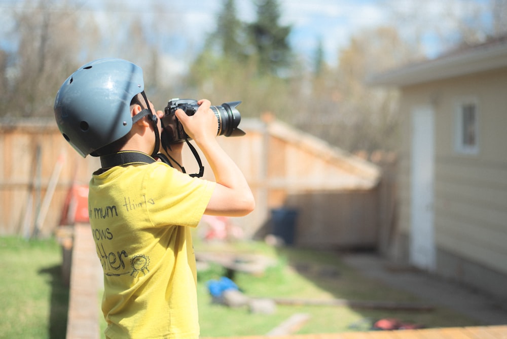 boy in yellow t-shirt using black dslr camera during daytime