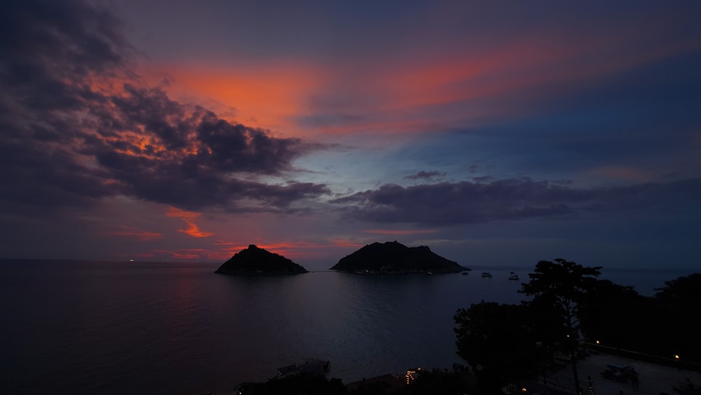 silhouette of mountain near body of water during sunset