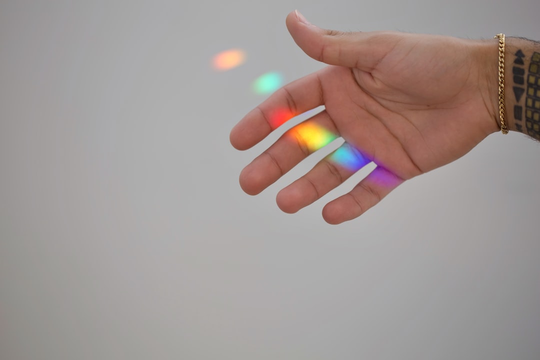 persons hand with purple manicure, Rainbow light reflex on the hand