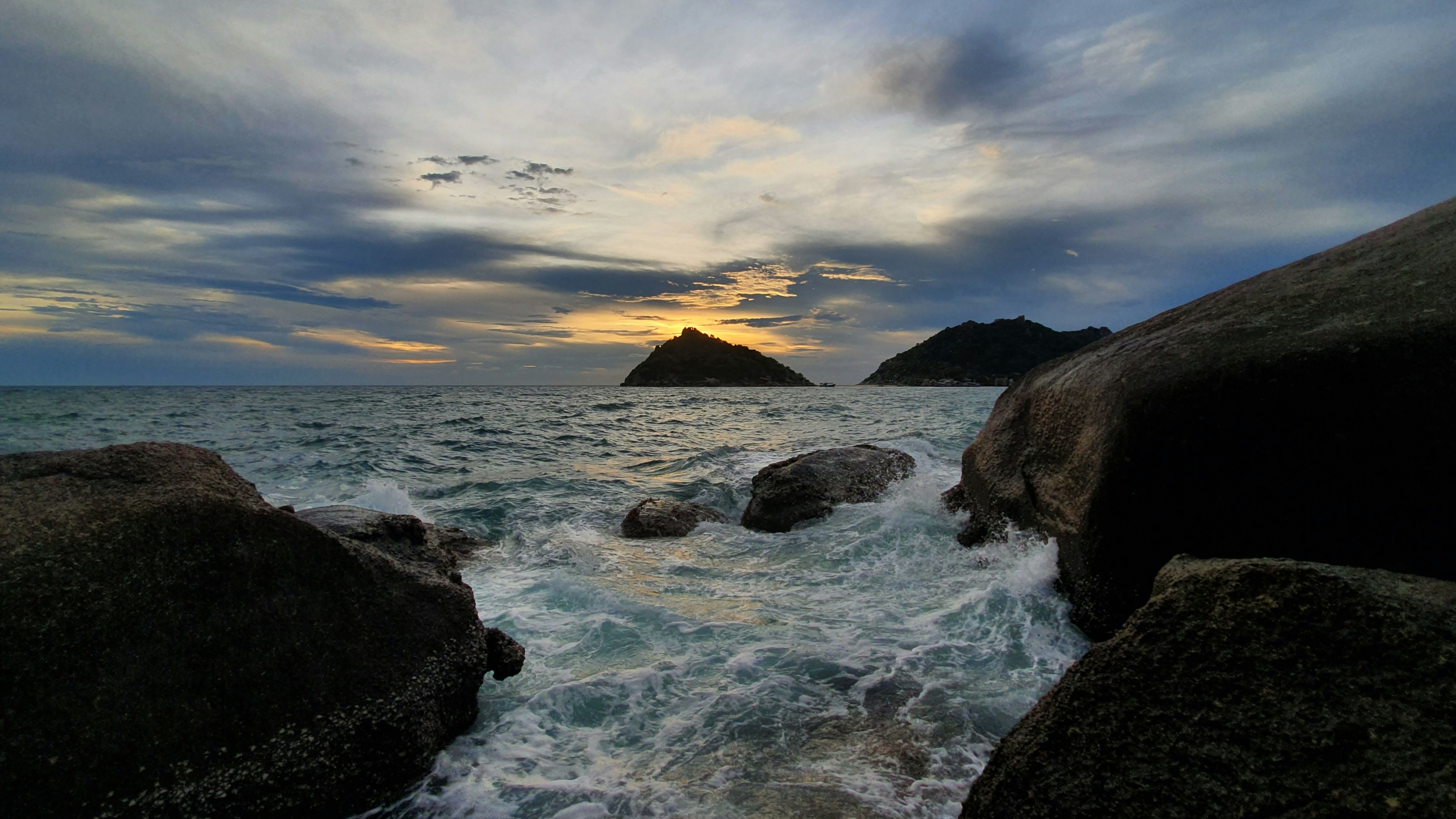 rocky shore under cloudy sky during sunset
