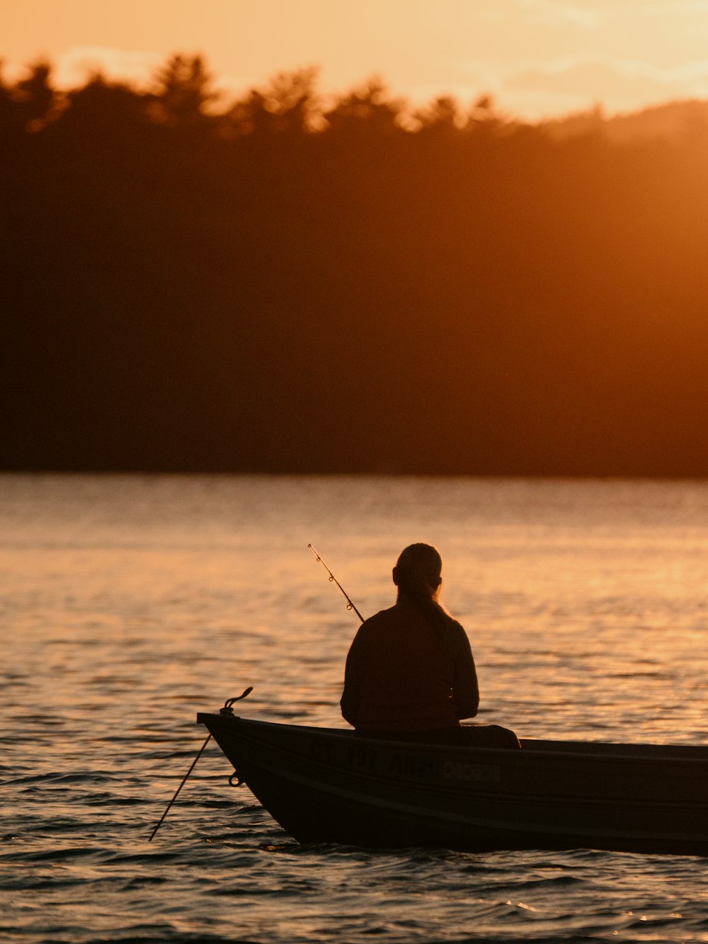 Silhouette eines Mannes, der bei Sonnenuntergang auf dem Boot fährt