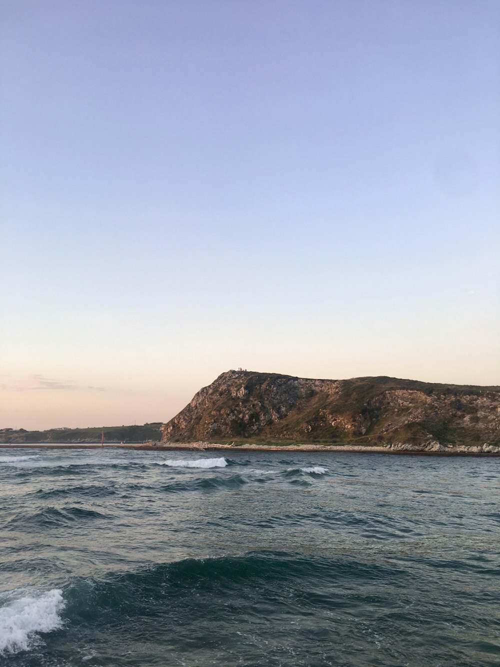 brown and green mountain beside body of water during daytime