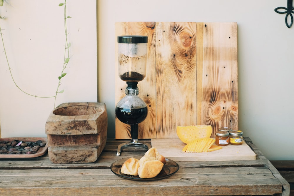 pain sur planche à découper en bois brun à côté d’un vase en verre noir et transparent