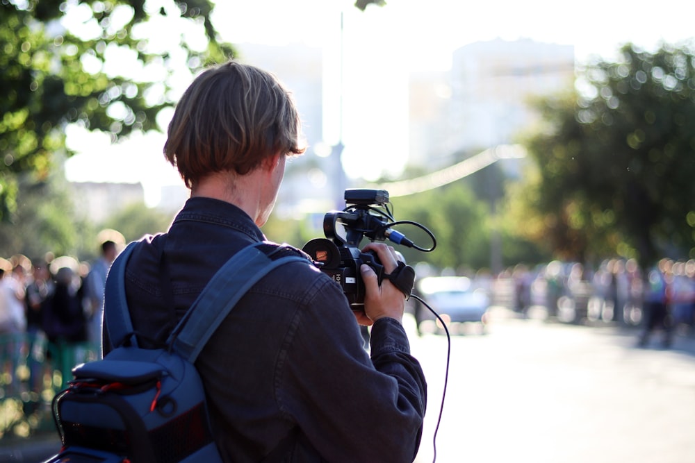 Mann in schwarzer Jacke mit schwarzer DSLR-Kamera