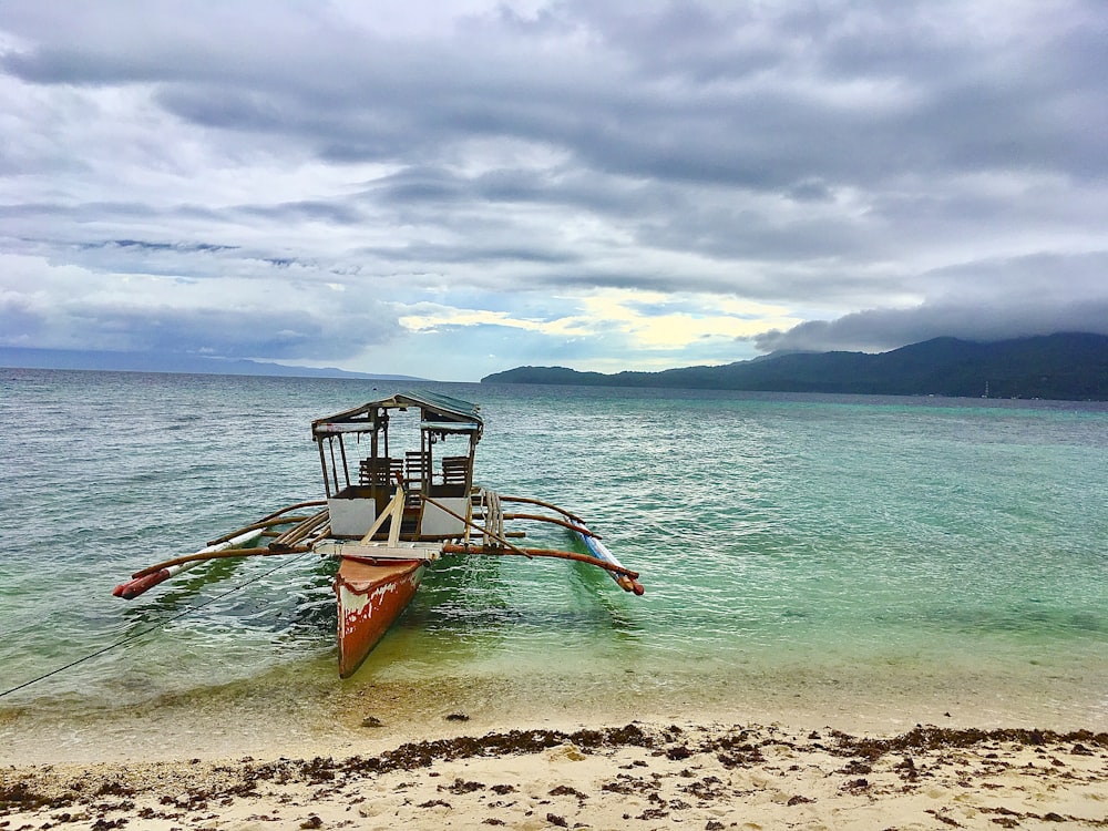 red and white boat on beach during daytime