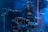 A woman stands confidently behind a drum set on a stage filled with blue and purple lighting and haze effects. She is wearing a dark leather jacket and a crop top, suggesting a rock or music performance setting. Her raised arm and focused expression convey a sense of energy and presence.