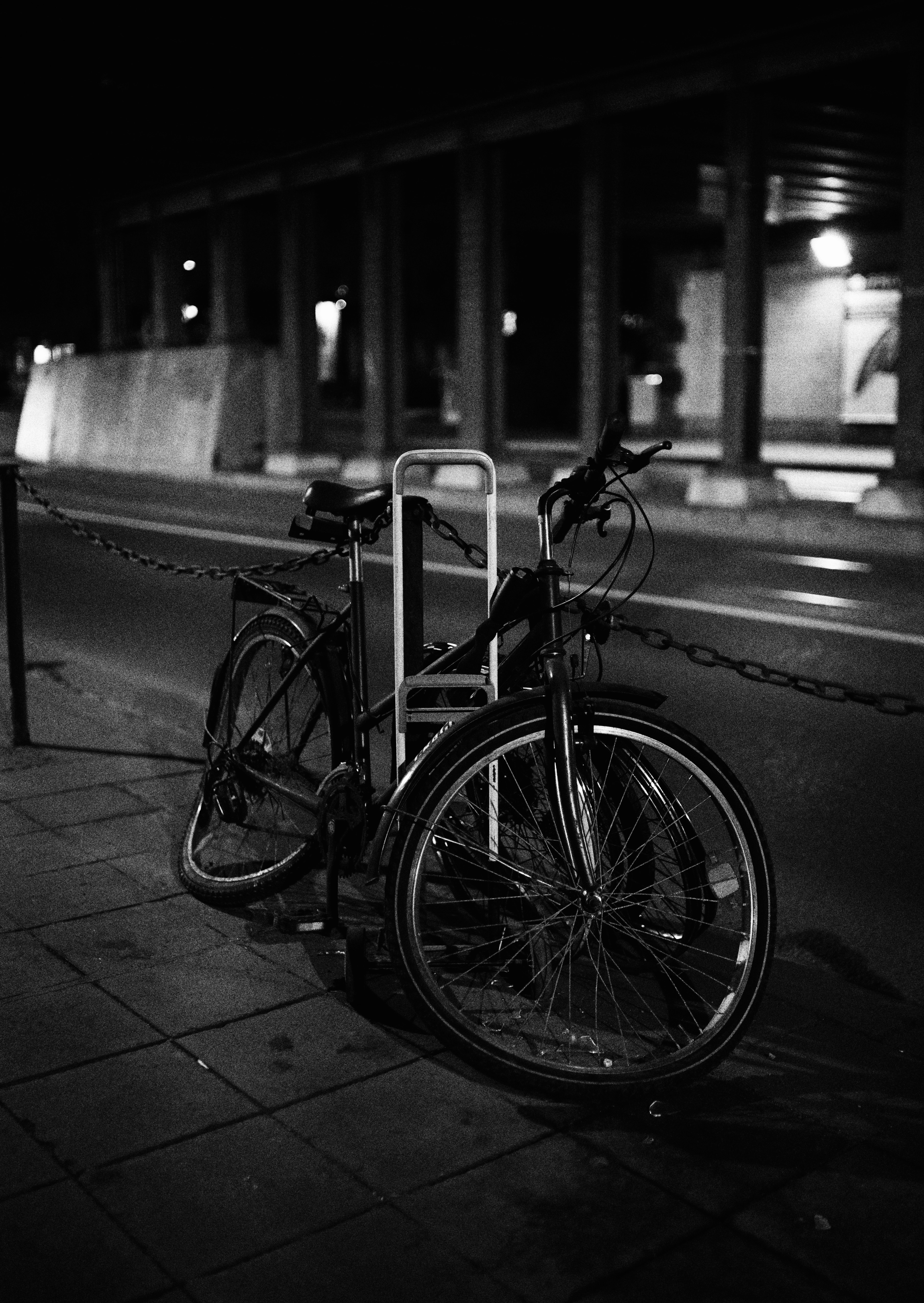 grayscale photo of city bicycle parked beside road