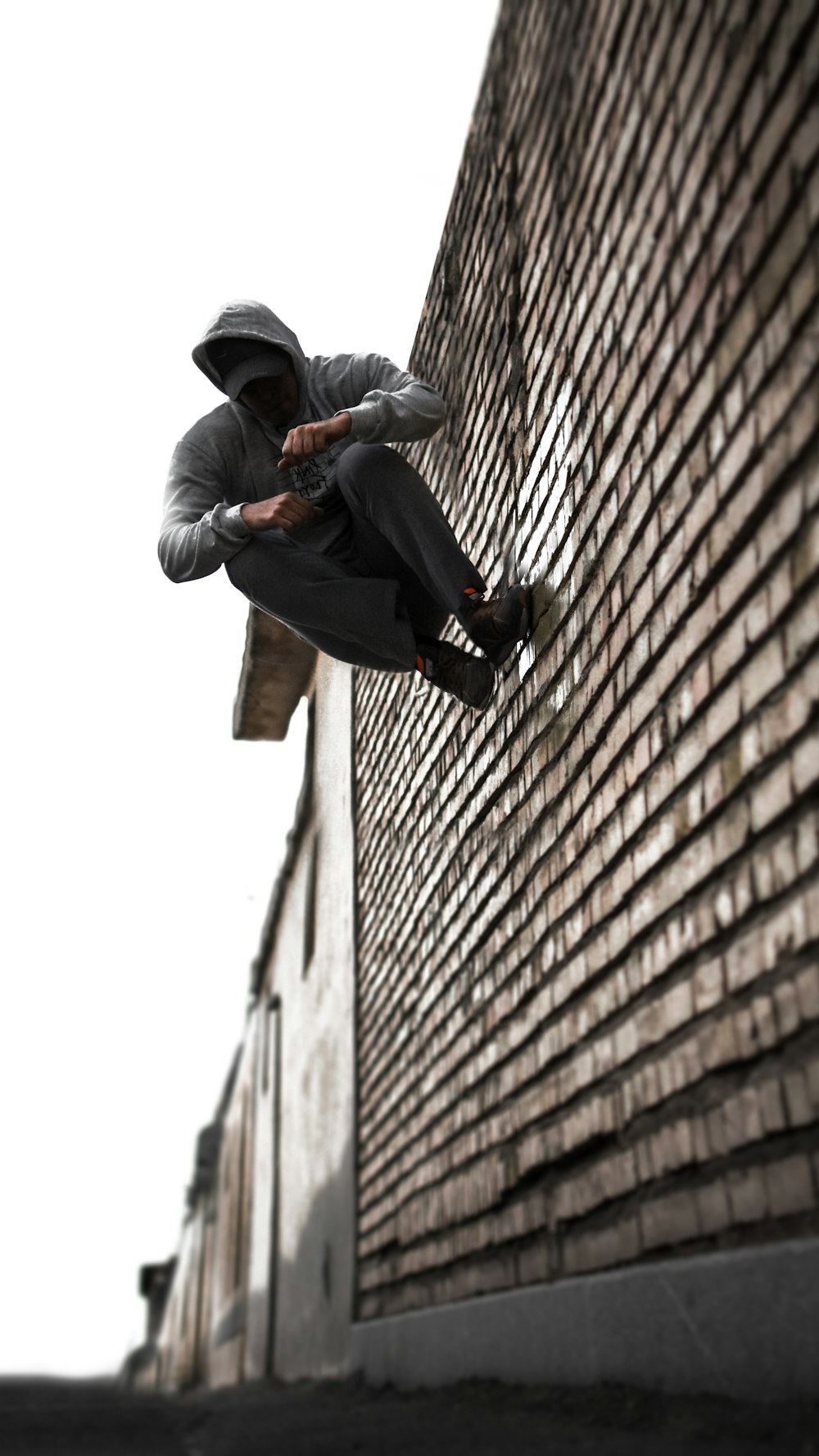 man in black jacket and black pants sitting on brown brick wall during daytime