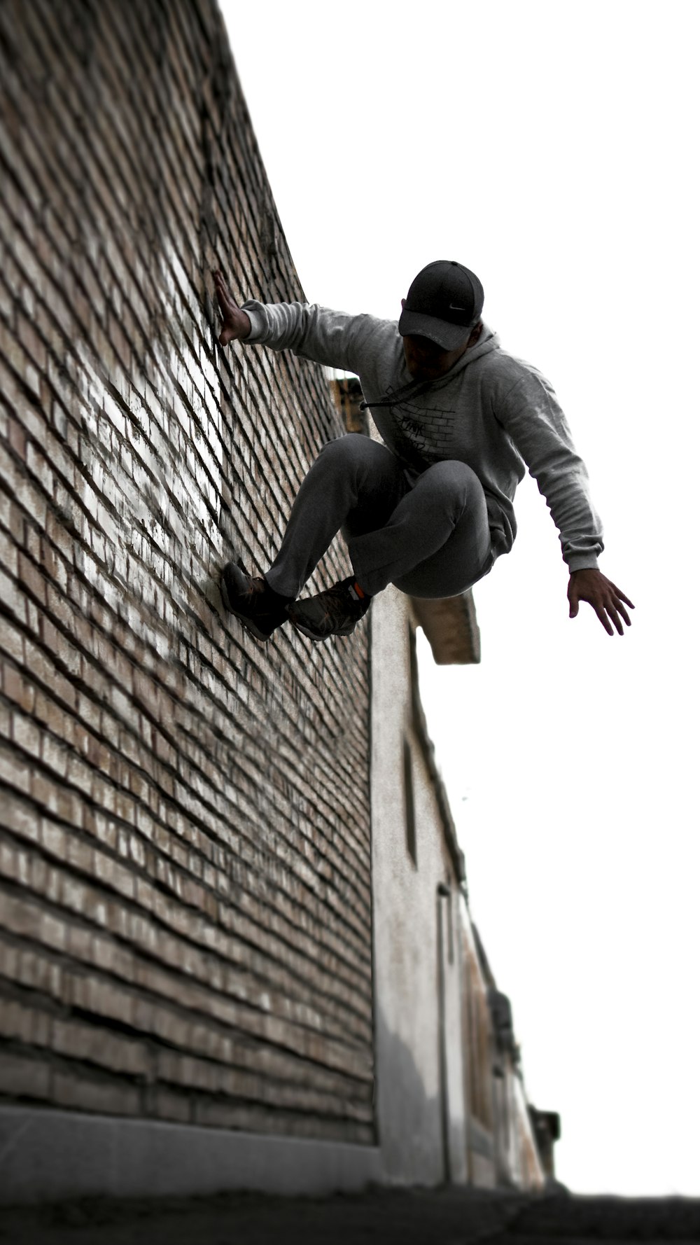 man in gray jacket and black pants sitting on brown brick wall during daytime