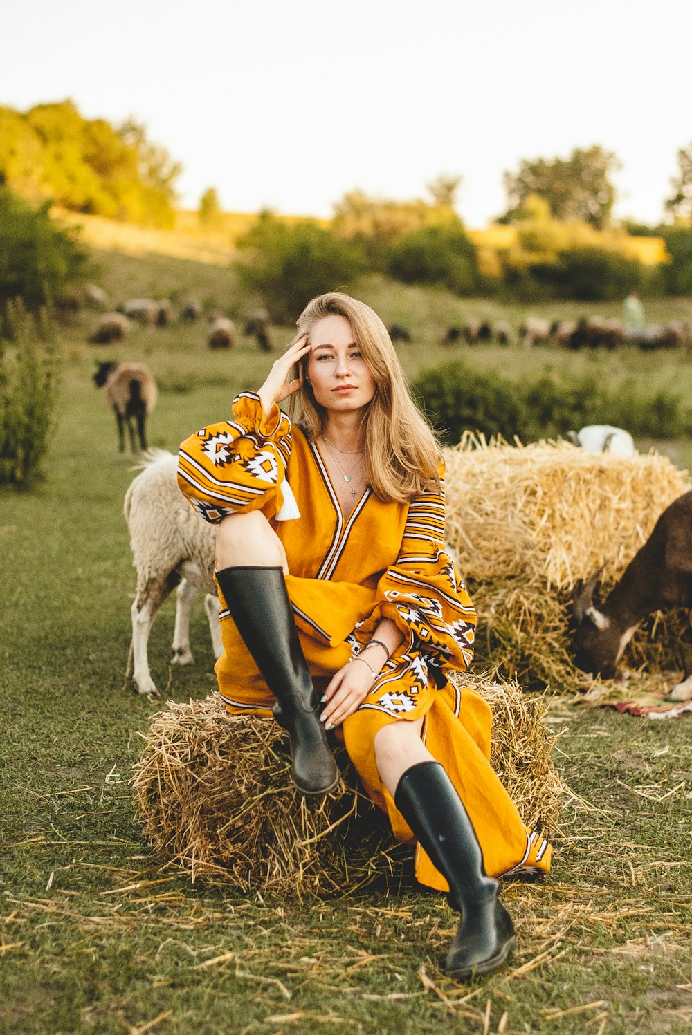 woman in orange and black dress sitting on brown grass field during daytime