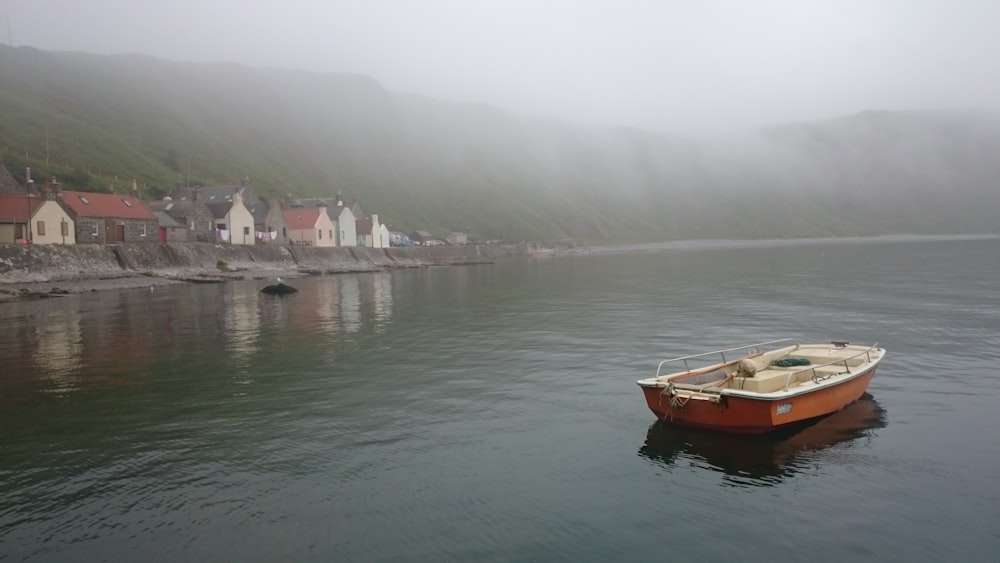 brown boat on body of water near city during foggy weather