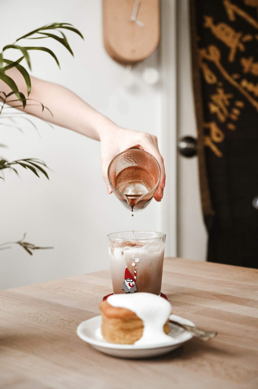 person pouring brown liquid on clear drinking glass