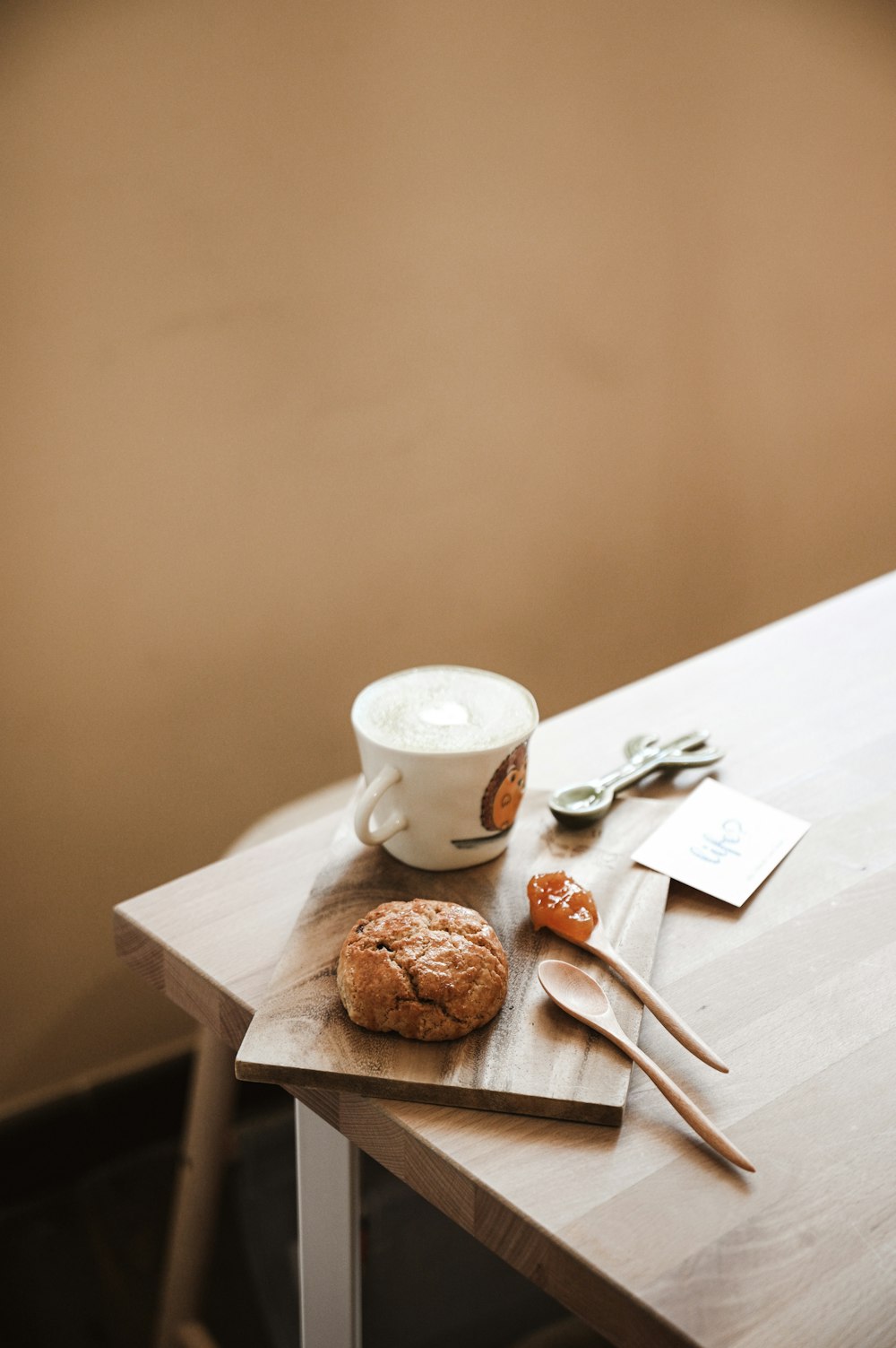 white ceramic mug beside brown bread on white wooden table