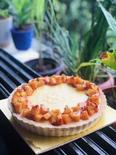 A vibrant fruit tart placed on a white plate with mint leaves.