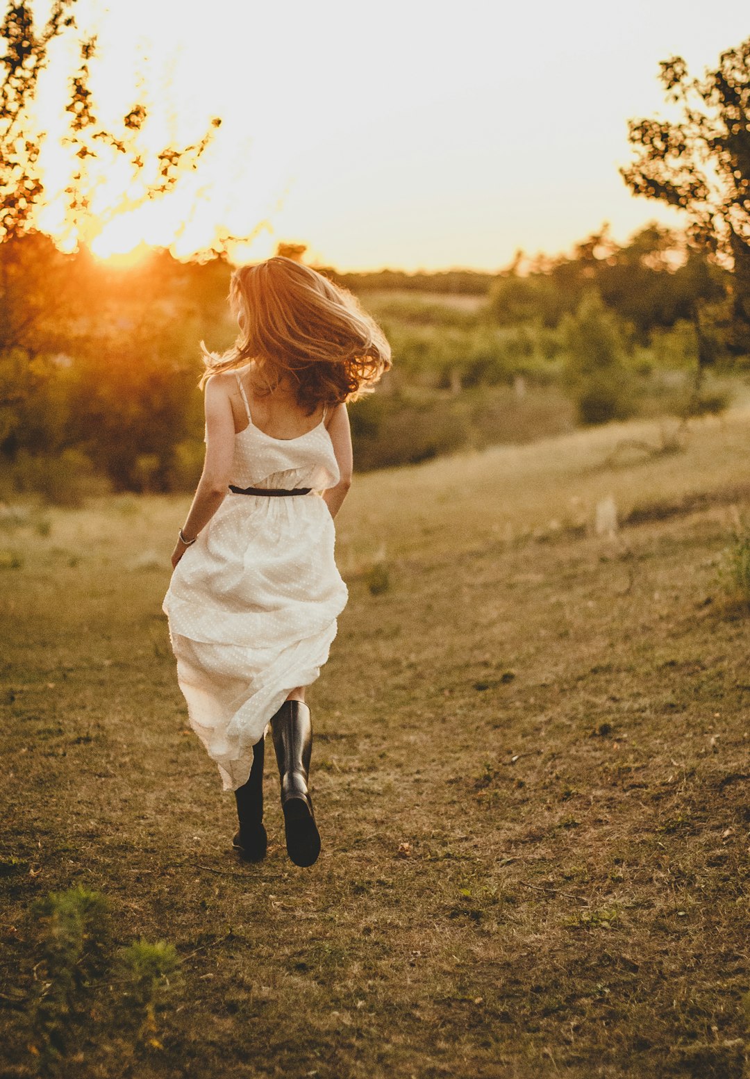 girl in white dress walking on green grass field during daytime