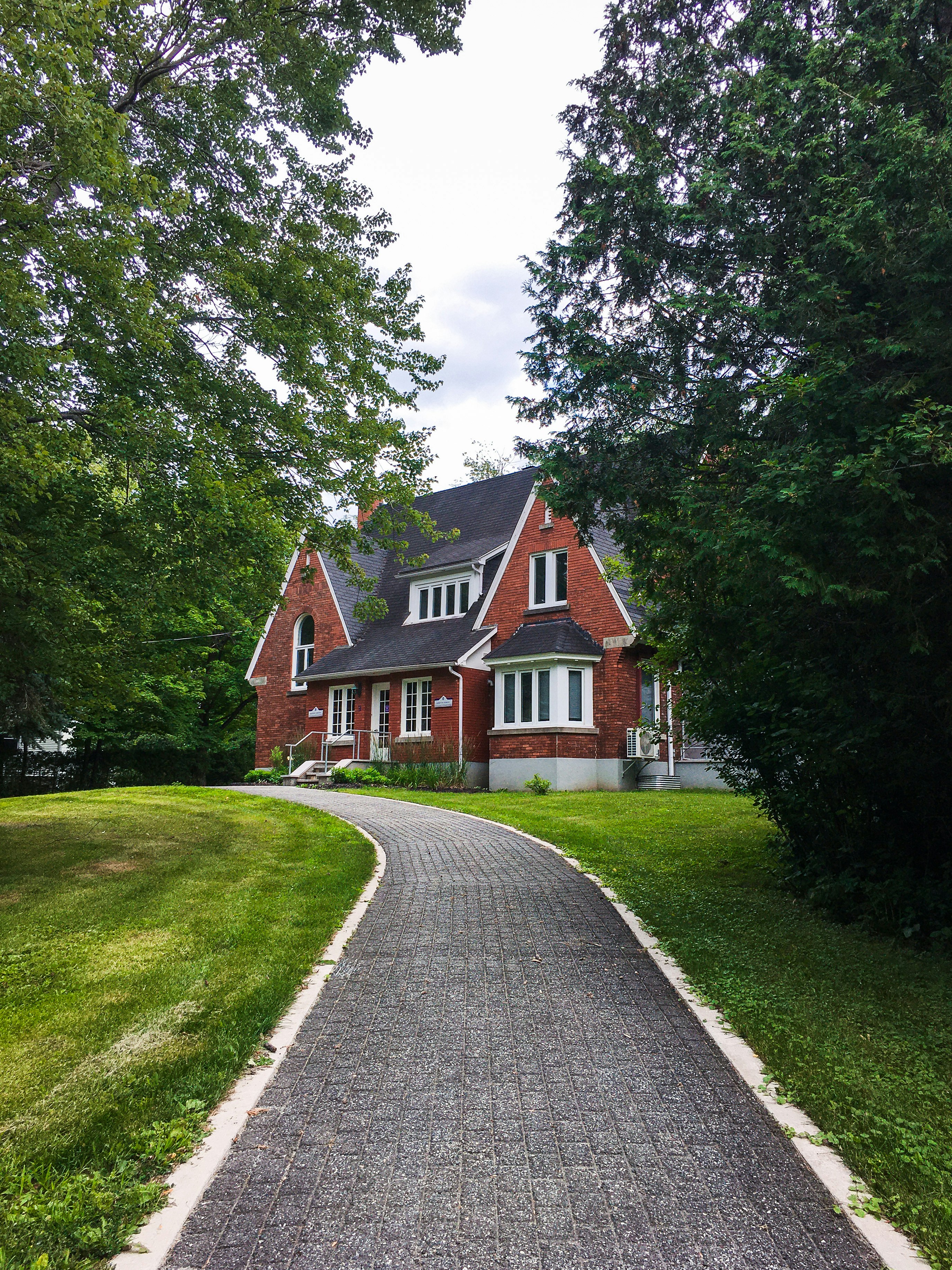 Brown and white house near green trees under white sky during daytime ...