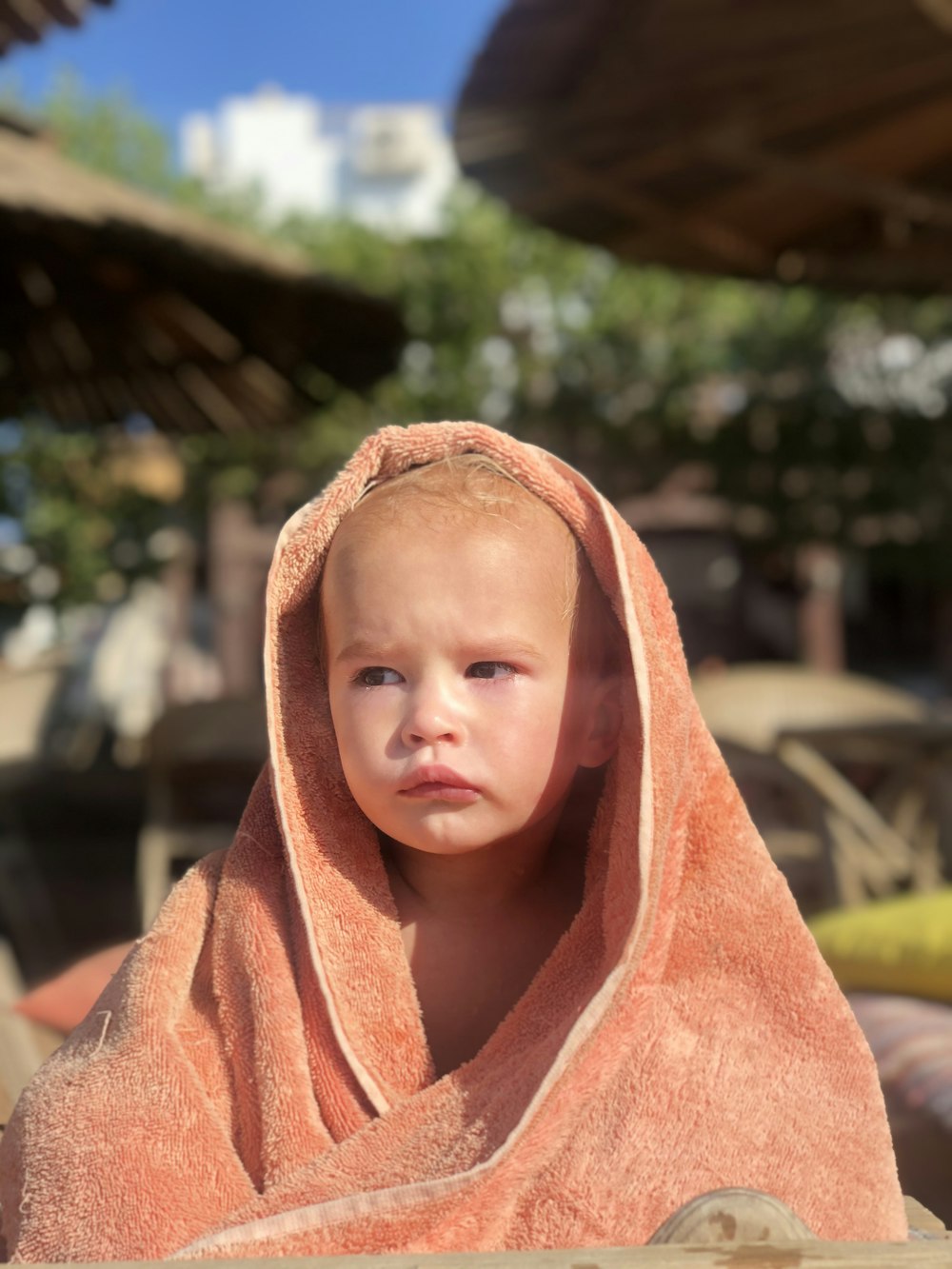 a little boy wrapped in a towel looking at the camera