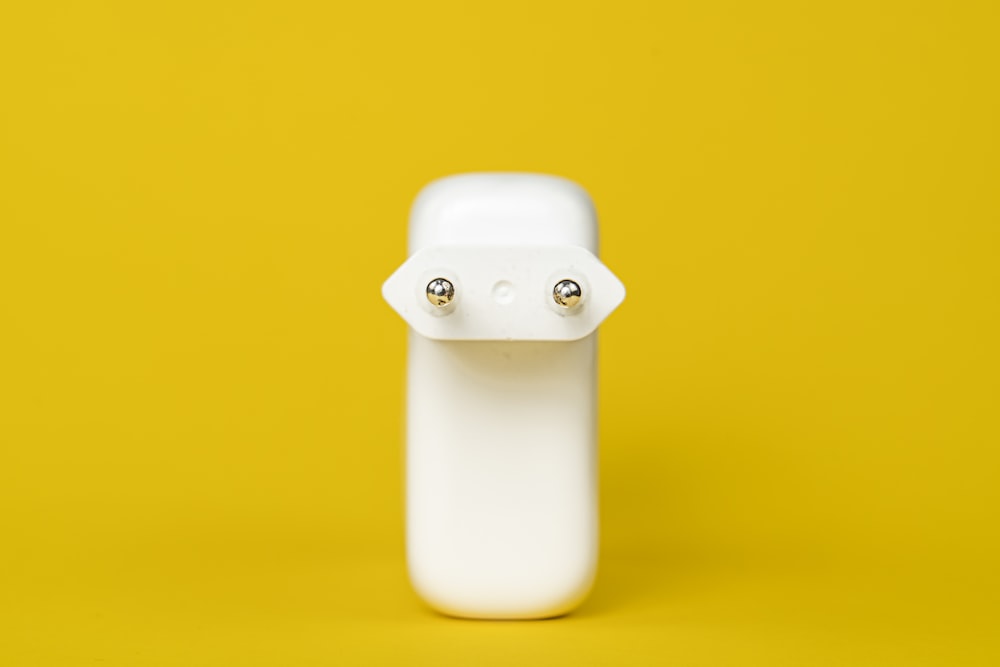 Botella de plástico blanca sobre superficie amarilla