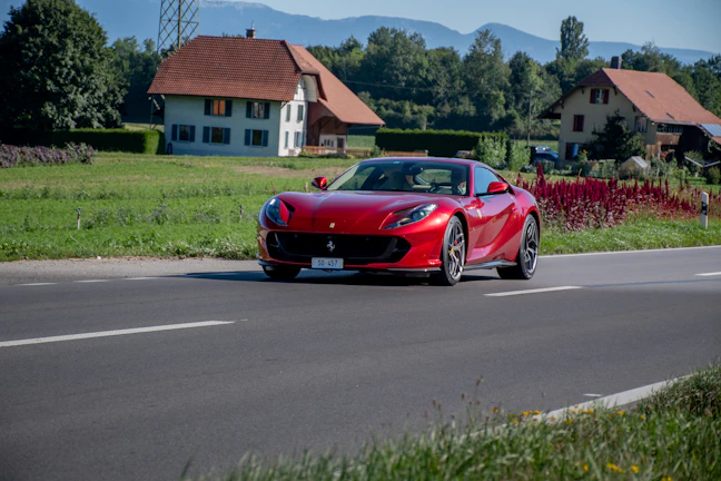 A sleek red sports car speeding along a coastal highway at sunset.