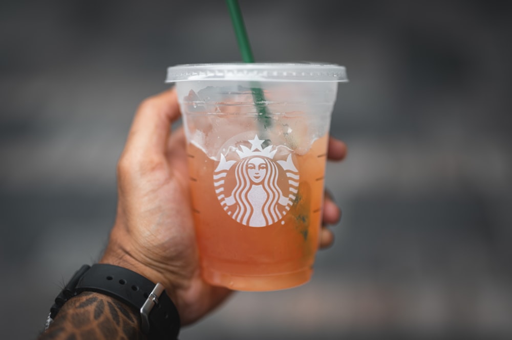 a hand holding a starbucks drink with a green straw