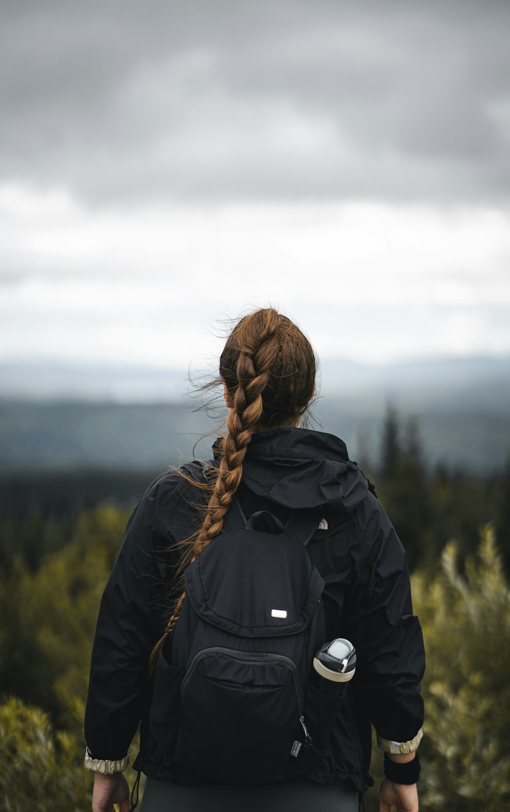 woman in black jacket standing on green grass field during daytime